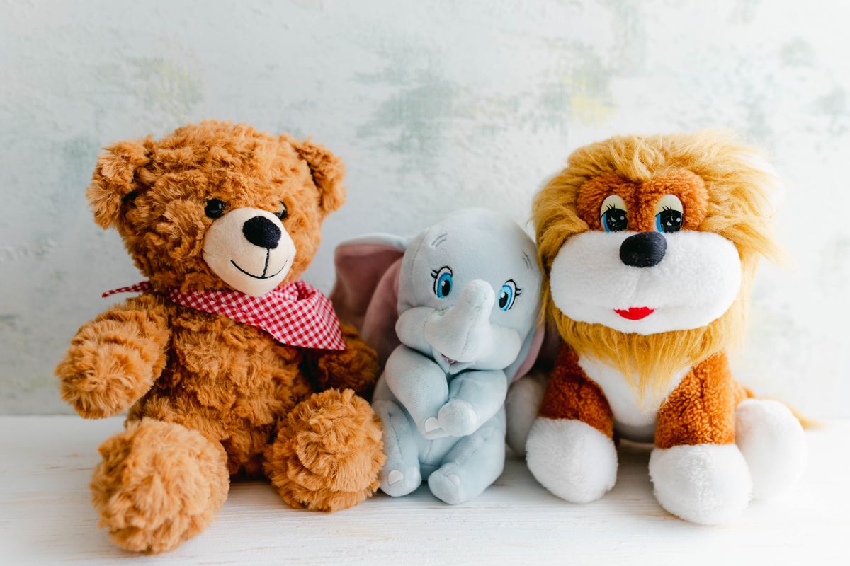 A teddy bear, elephant, and lion plush together